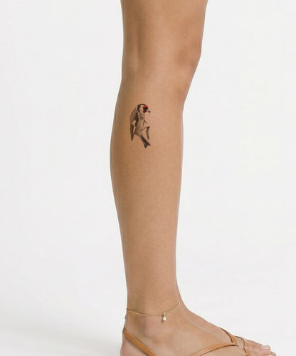 Tatueringsdesign med steglits som äter från tistel